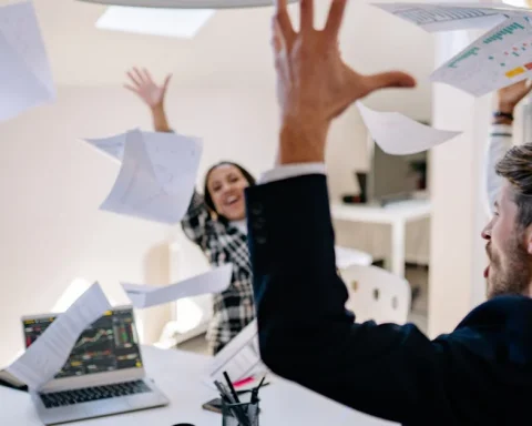 Duas pessoas em um escritório jogando papéis para o alto em celebração.